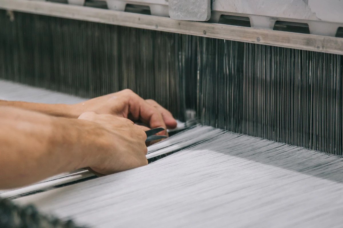 Textile specialist inspecting threads on a weaving loom