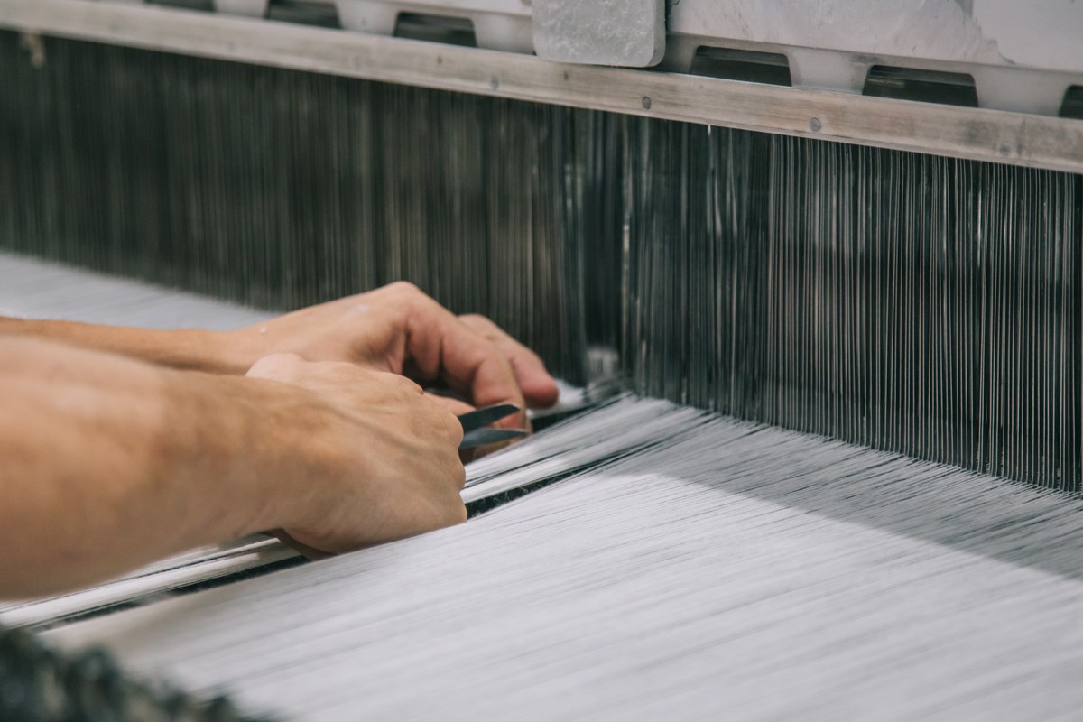 Textile specialist inspecting threads on a weaving loom
